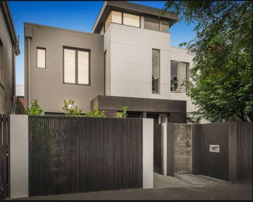 uma casa branca com uma cerca à frente. em Modern South Melbourne Town House. em Melbourne