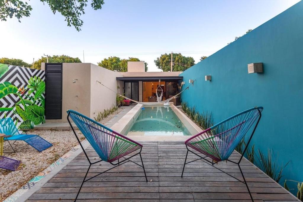 a backyard with two chairs and a swimming pool at CASA YAXCHE luxury house in downtown Mérida in Mérida