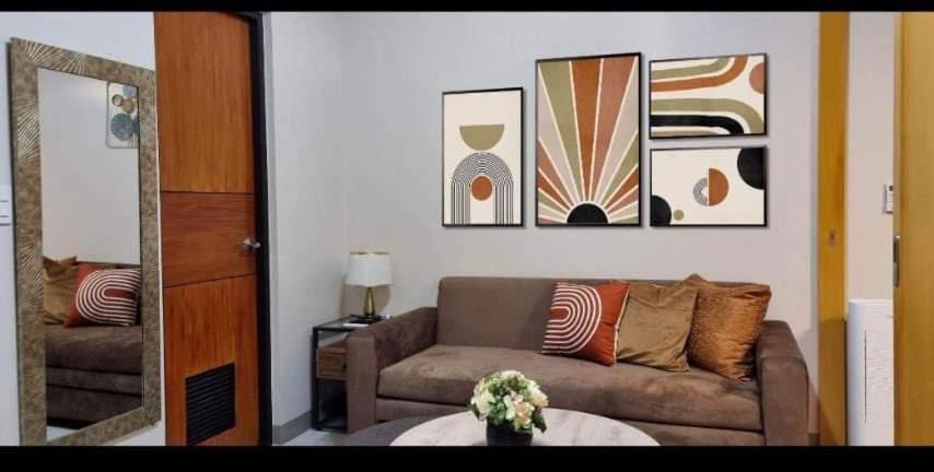 a living room with a couch and pictures on the wall at Elegant and spacious one bedroom in BGC in Manila