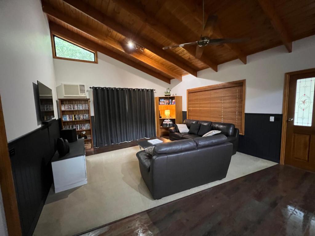 a living room with black leather furniture and a window at The Kingfisher Lodge 111 in Halls Gap