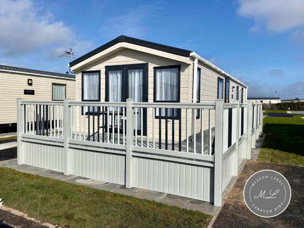 ein winziges Haus mit einem weißen Zaun in der Unterkunft Palm Grove 183 - Golden Palm - Pet friendly, WiFi, central heating, bed linen - Meadow Lakes Caravan & Lodge Hire in Chapel Saint Leonards