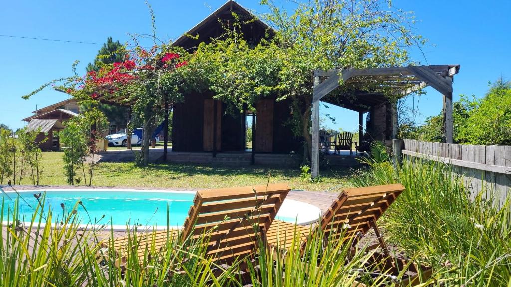 a house with a swimming pool and two chairs at Chalé privativo/Lareira/Wi-Fi in Osório