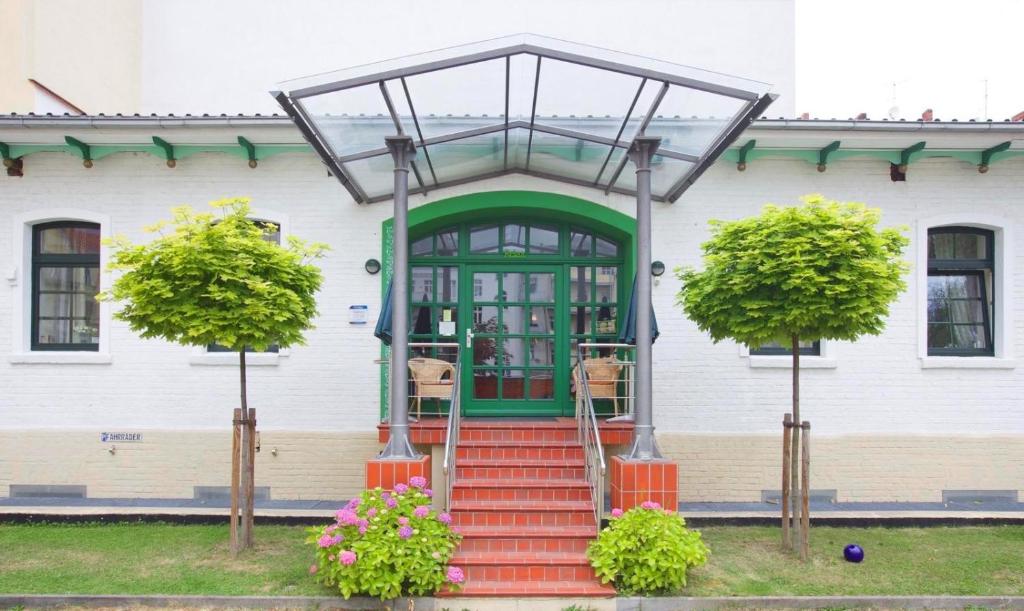 ein weißes Haus mit einer grünen Tür und einer Treppe in der Unterkunft Zum Grünen Tor - ganzheitliche Pension in Görlitz