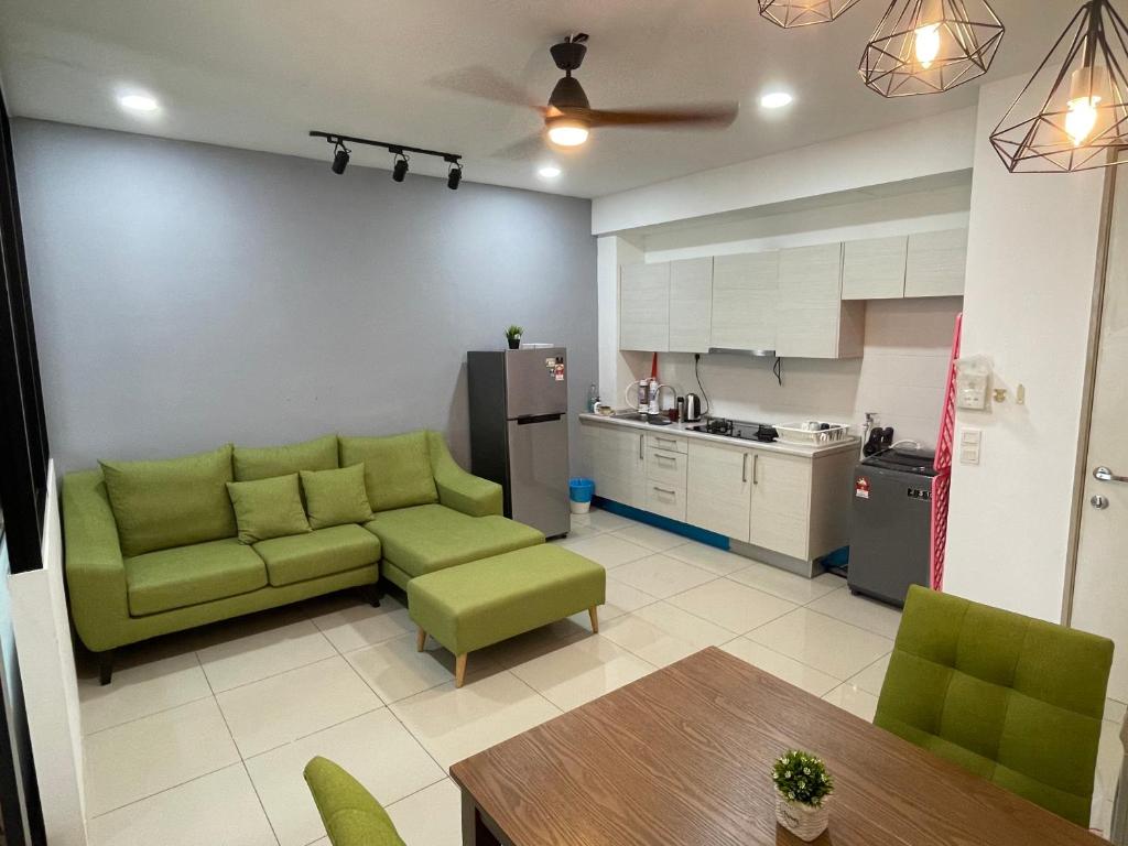 salon z zieloną kanapą i kuchnią w obiekcie Nice & Comfy Studio in Greenfield Regency w mieście Johor Bahru