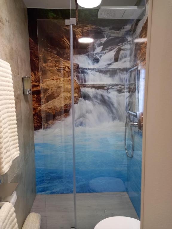 a bathroom with a shower with a waterfall mural at La Cascade et des Halles in Dijon