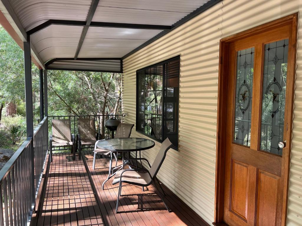 a porch with a table and chairs and a door at The Kingfisher Lodge 111 in Halls Gap