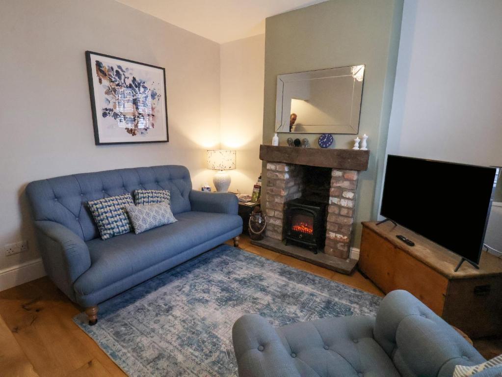 a living room with a blue couch and a fireplace at Bumblebee Cottage in Beverley