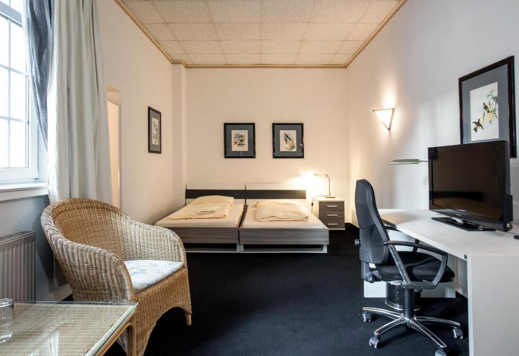 een kamer met 2 bedden, een bureau en een computer bij Hotel Alte Fabrik in Mettmann