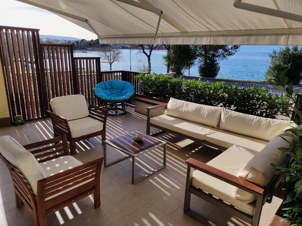 a patio with a couch and chairs and a view of the water at apartman Emili in Malinska