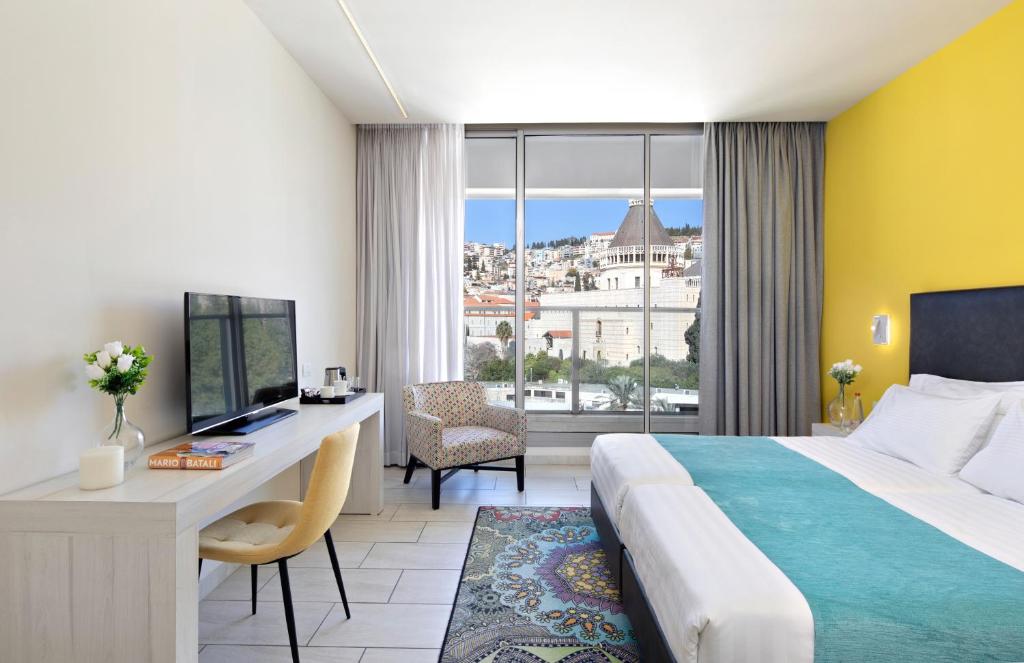 a hotel room with a bed and a desk and a window at Legacy Hotel ַ& Convention Center Nazareth in Nazareth