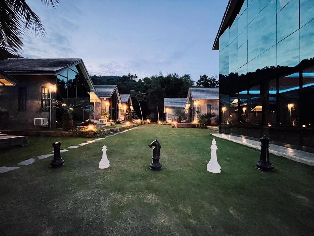 a group of eight chess pieces on a lawn in front of a building at El Vaso Resort in Ban Map Chalut