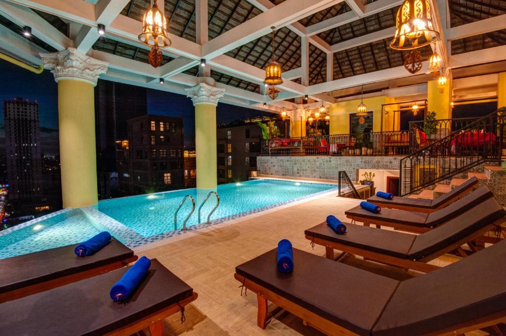 uma grande piscina num hotel com sofás e uma piscina em Khmer Surin Boutique Guesthouse em Phnom Penh