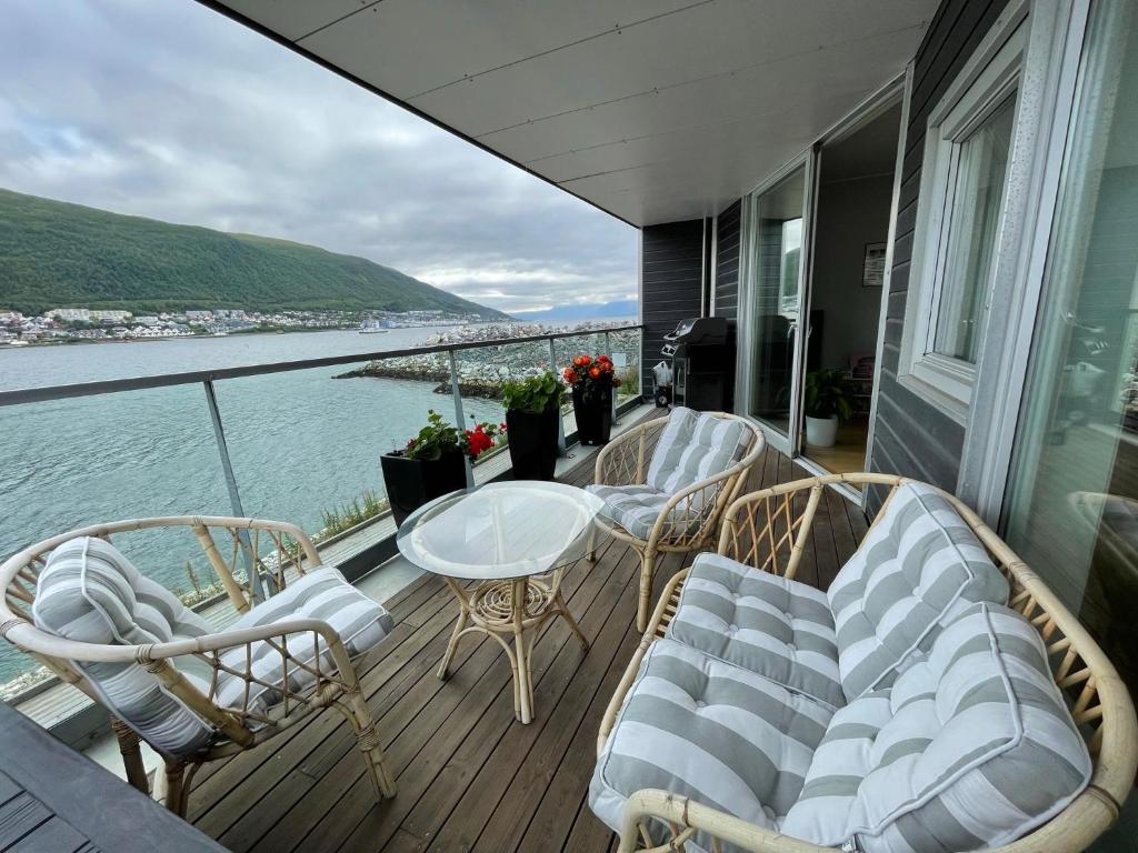 einen Balkon mit Stühlen, einem Tisch und Blick auf das Wasser in der Unterkunft Sea View City Apartment in Tromsø