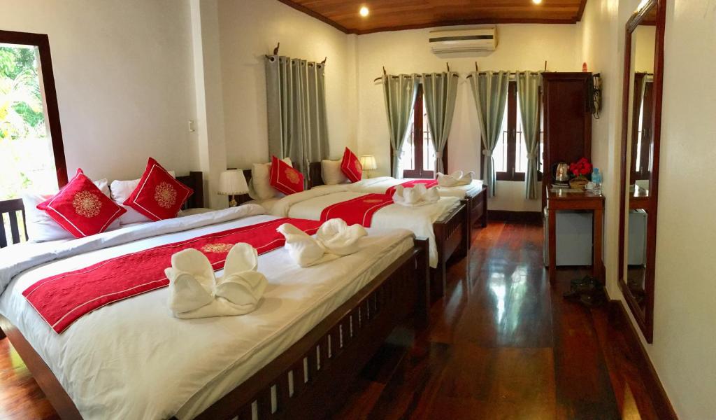a bedroom with two beds with red and white pillows at Luang Prabang Pangkham Lodge in Luang Prabang