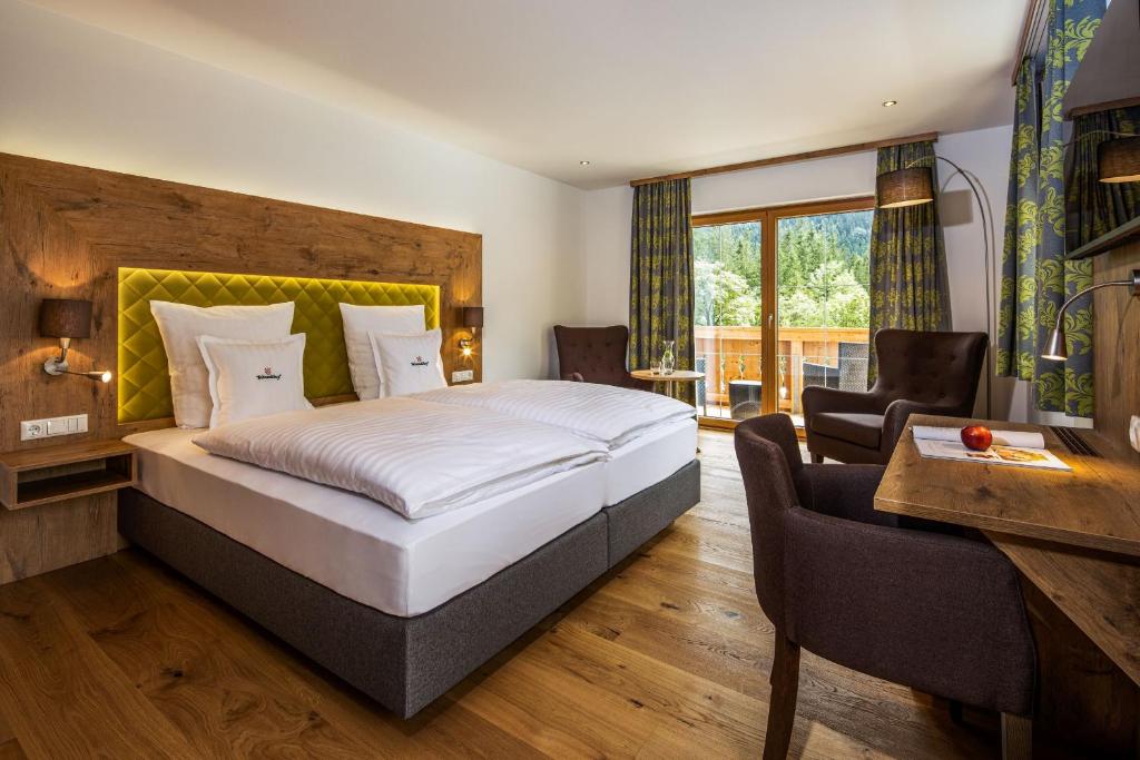 a hotel room with a large bed and a desk at Wörndlhof - Das Refugium in Ramsau
