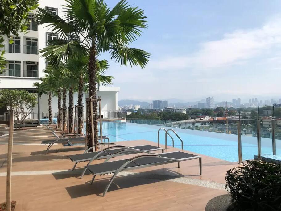 une piscine avec des chaises et des palmiers dans un bâtiment dans l'établissement Titiwangsa 6PX near monorail PWTC Infinity pool, à Kuala Lumpur