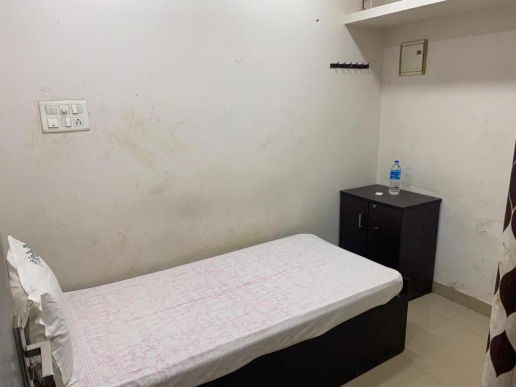 a small room with a bed and a black cabinet at Redbell Suites Calicut in Kozhikode