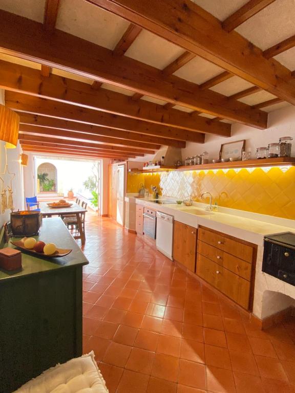 uma grande cozinha com paredes amarelas e tectos em madeira em Santa Rosalia em Ciutadella