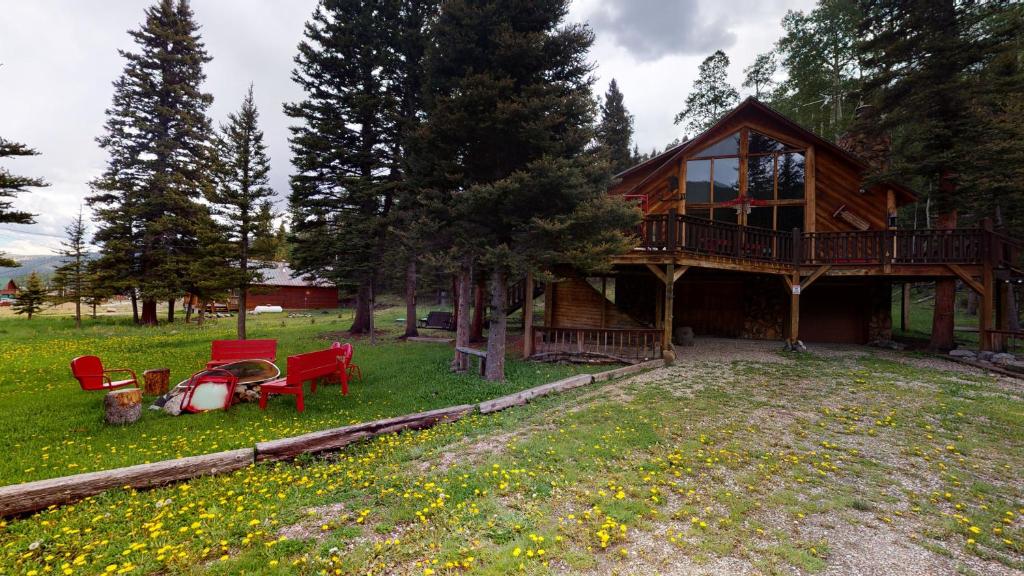 una casa de madera con terraza y sillas rojas en el patio en Standing Bear Lodge With High Speed Wifi, en Red River
