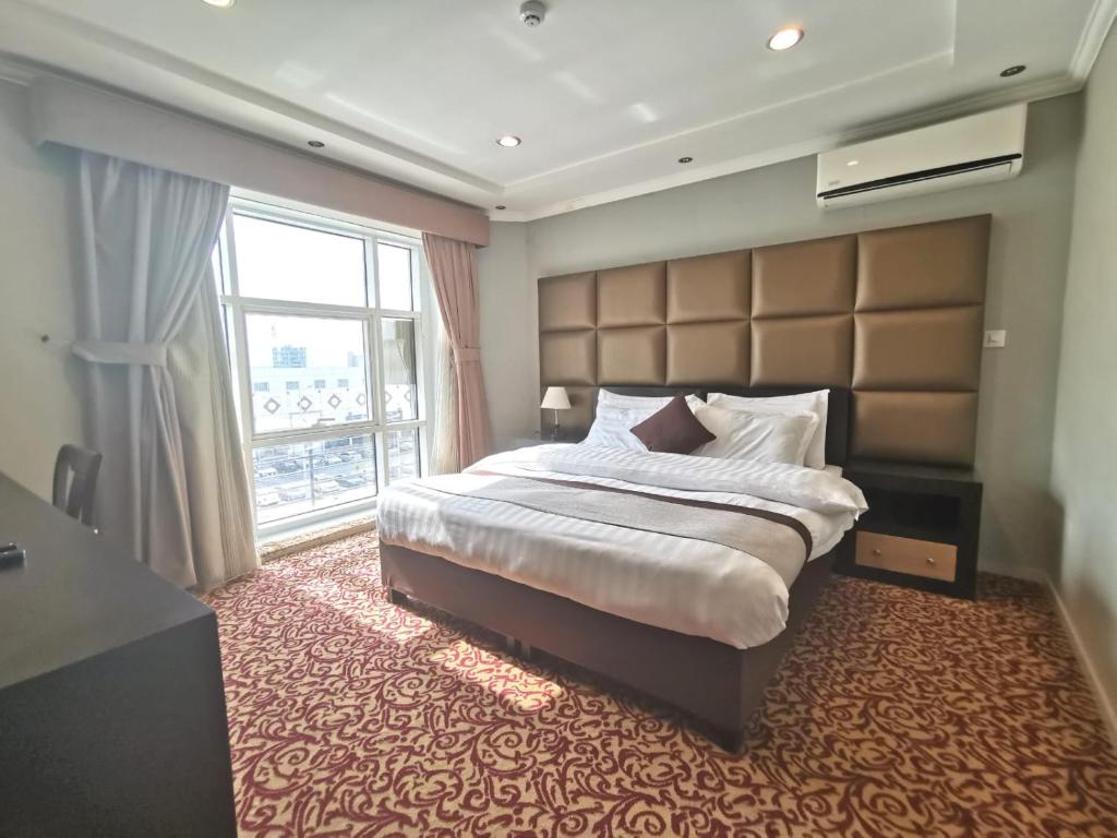 a bedroom with a large bed and a large window at Ashbonh Hotel Suites in Riyadh