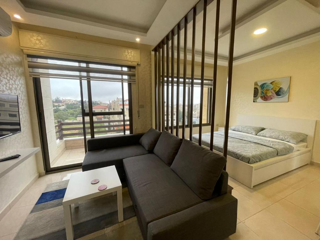 een woonkamer met een bank en een bed bij Jubeiha View Apartments in Amman