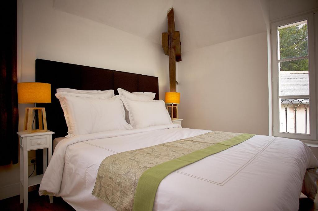 a bedroom with a large white bed and a window at Gîte l'écurie in Larçay