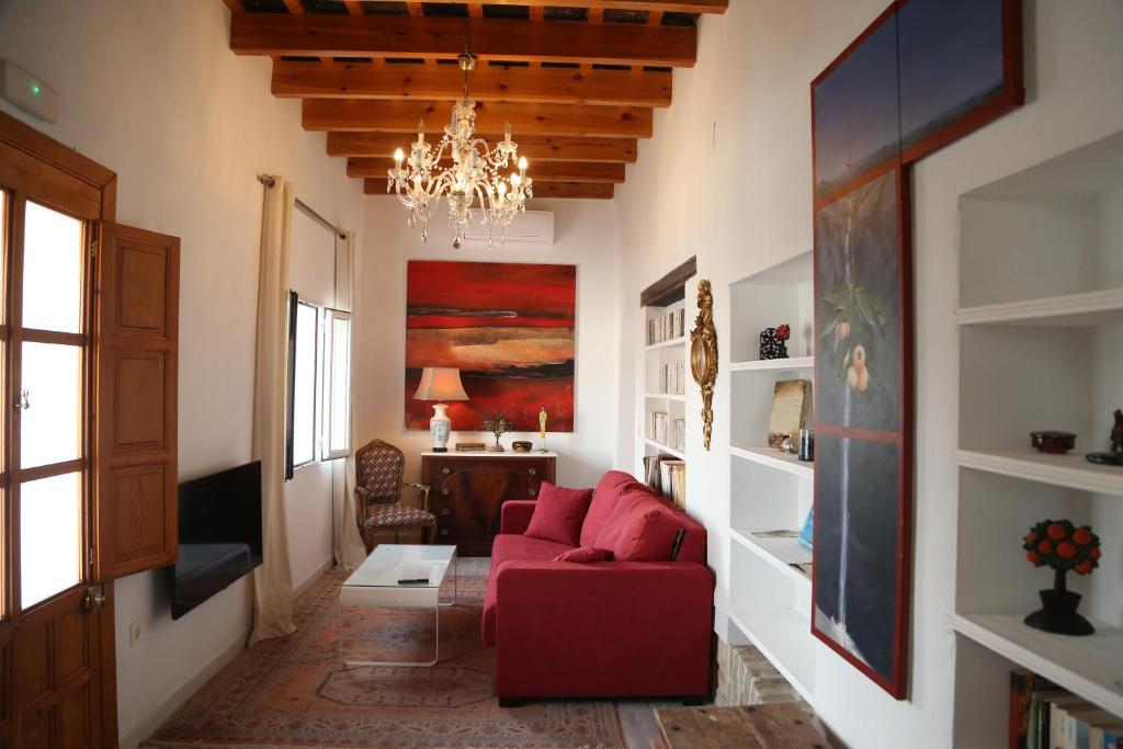 sala de estar con sofá rojo y lámpara de araña en Casa de la Fra, en Jerez de la Frontera
