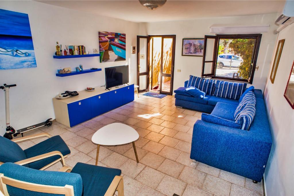 a living room with blue couches and a tv at Villa Laura - Putzu Idu in Putzu Idu
