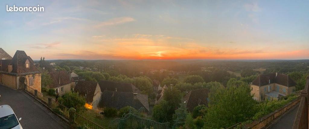 einen Sonnenuntergang über einer Stadt mit Häusern und Bäumen in der Unterkunft Belle vue in Gourdon-en-quercy