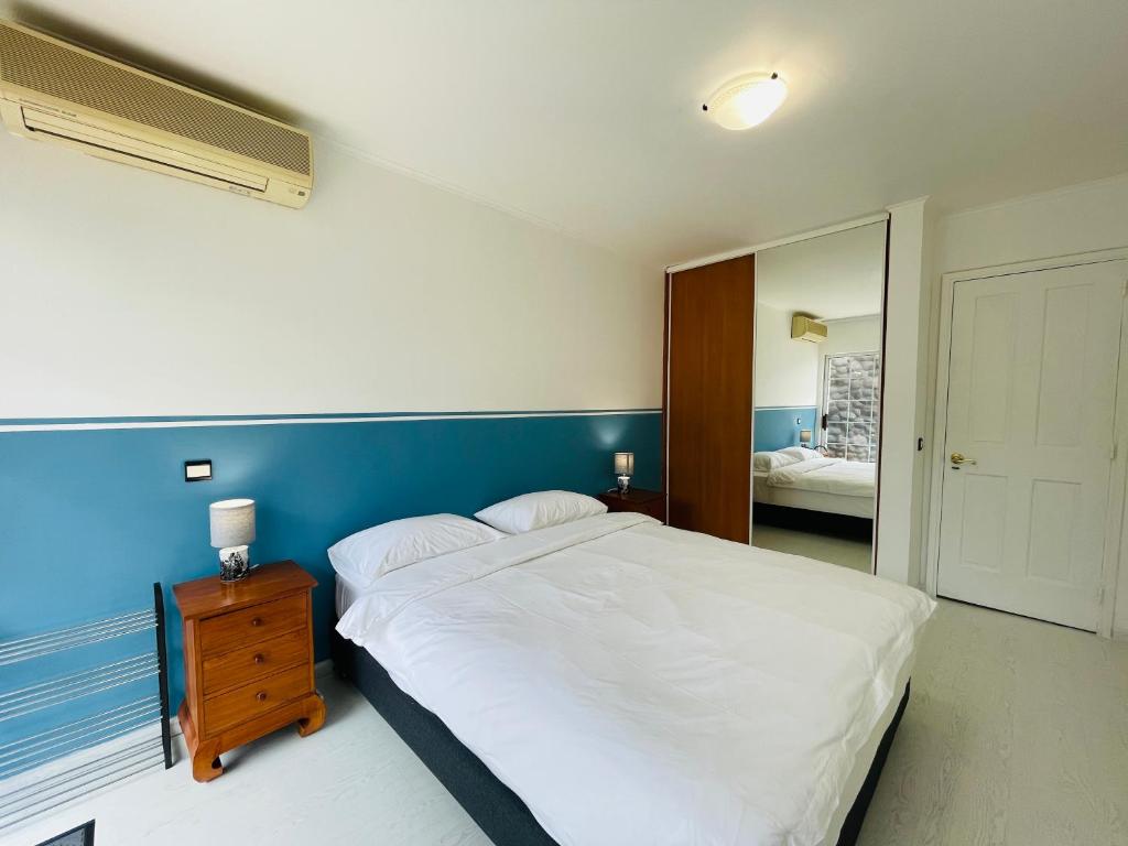- une chambre avec un lit blanc et un mur bleu dans l'établissement REA Lodge, à Punaauia