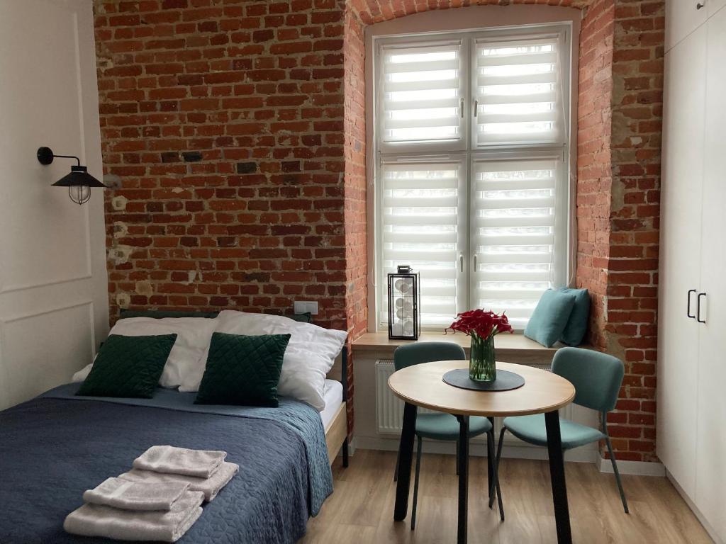 sypialnia z łóżkiem, stołem i ceglaną ścianą w obiekcie przytulnie w Łodzi w Łodzi