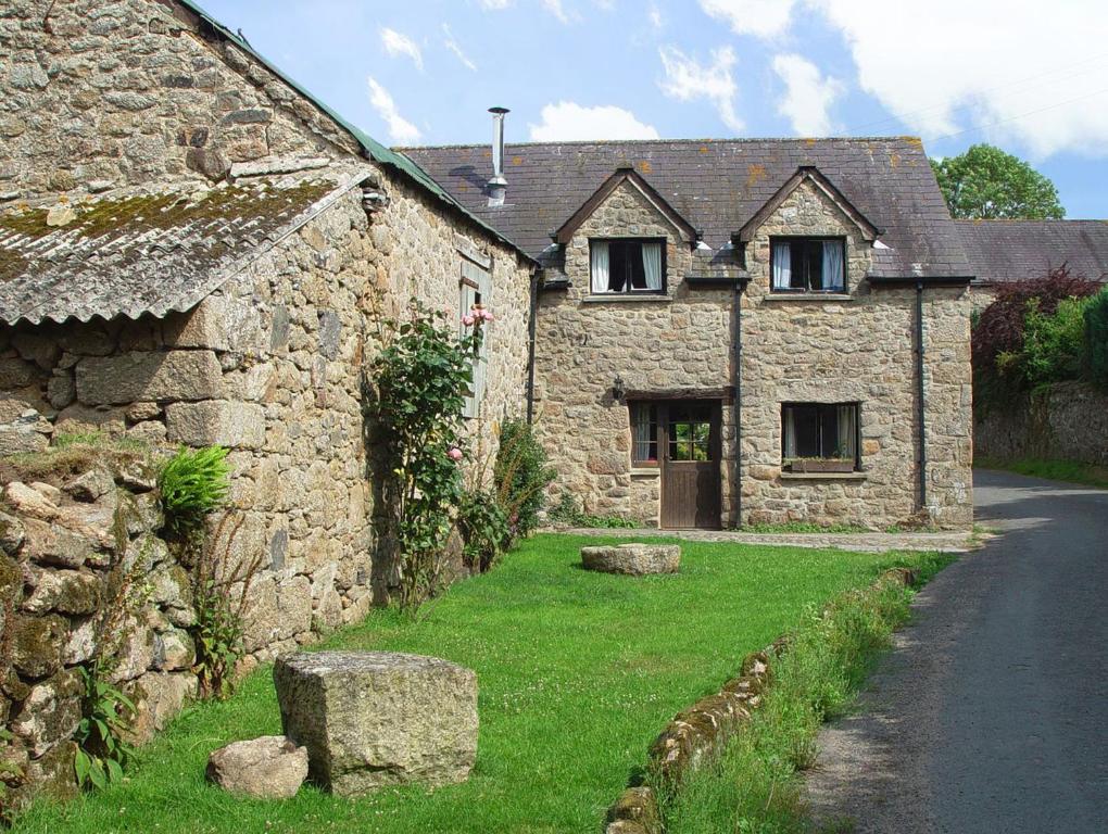 an old stone house with a grass yard next to a road at The Cottage in Moretonhampstead