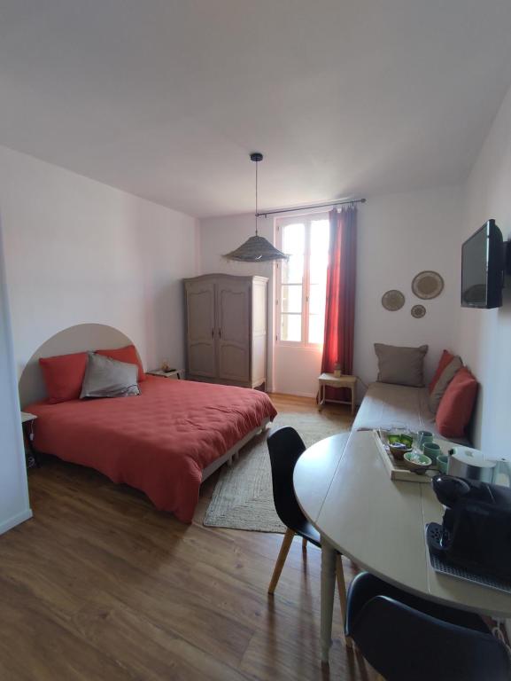 um quarto com uma cama vermelha e uma mesa em La Provinciale en Ville em Montélimar
