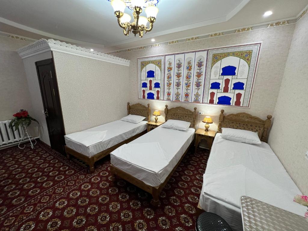 Habitación con 3 camas y lámpara de araña. en ''NAVO'' Guest House, en Bukhara