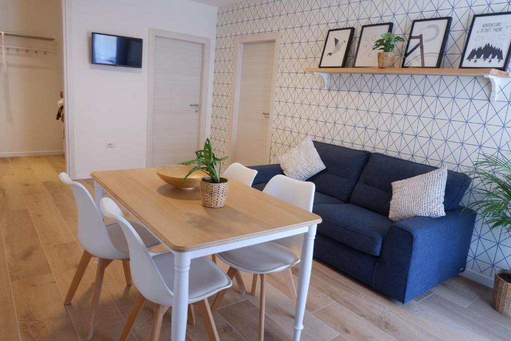 sala de estar con mesa y sofá azul en Casa Barcelli Sport & Family Apartments, en Nago-Torbole