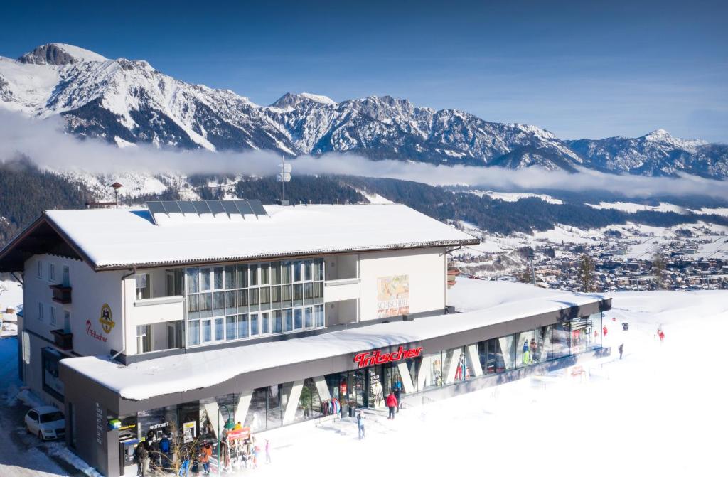 a building on a ski slope with mountains in the background at Aparthotel Tritscher in Schladming