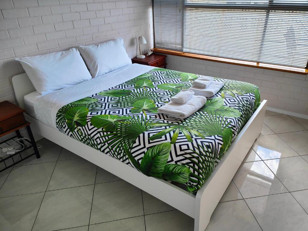 a bed with a green and white comforter with towels on it at Tuggeranong Short Stay #08 - Sleeps 6 in Tuggeranong