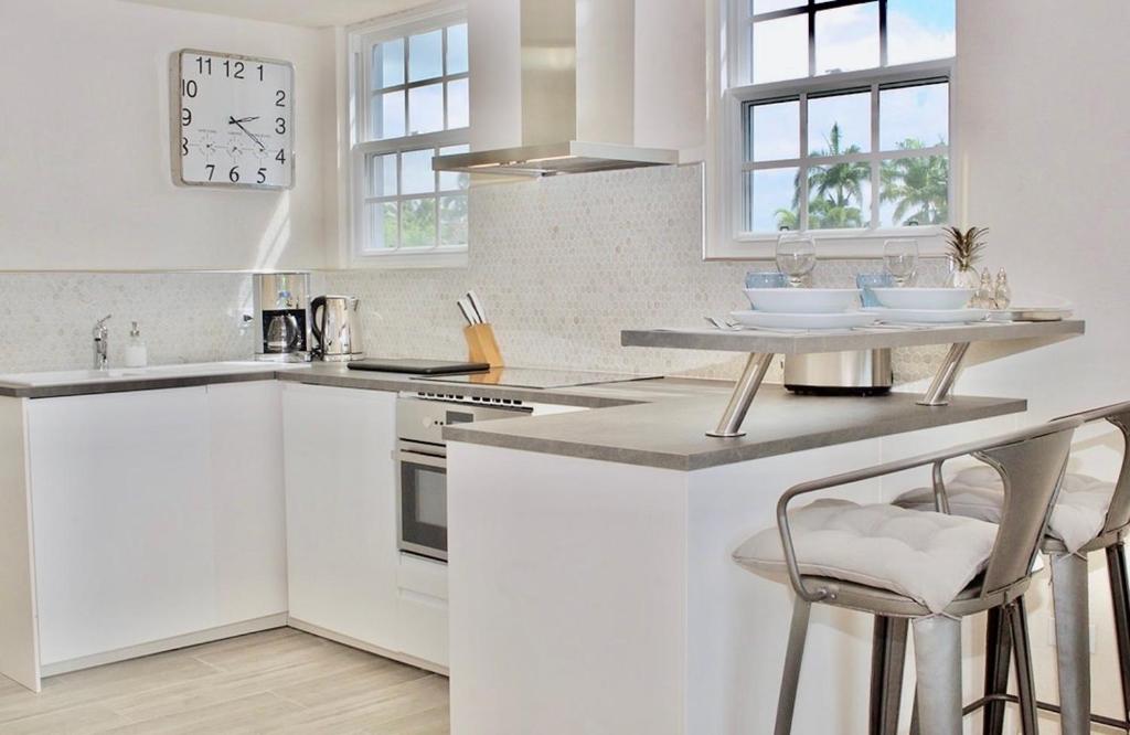 a kitchen with white cabinets and a counter with stools at West Rock Villas in Saint James