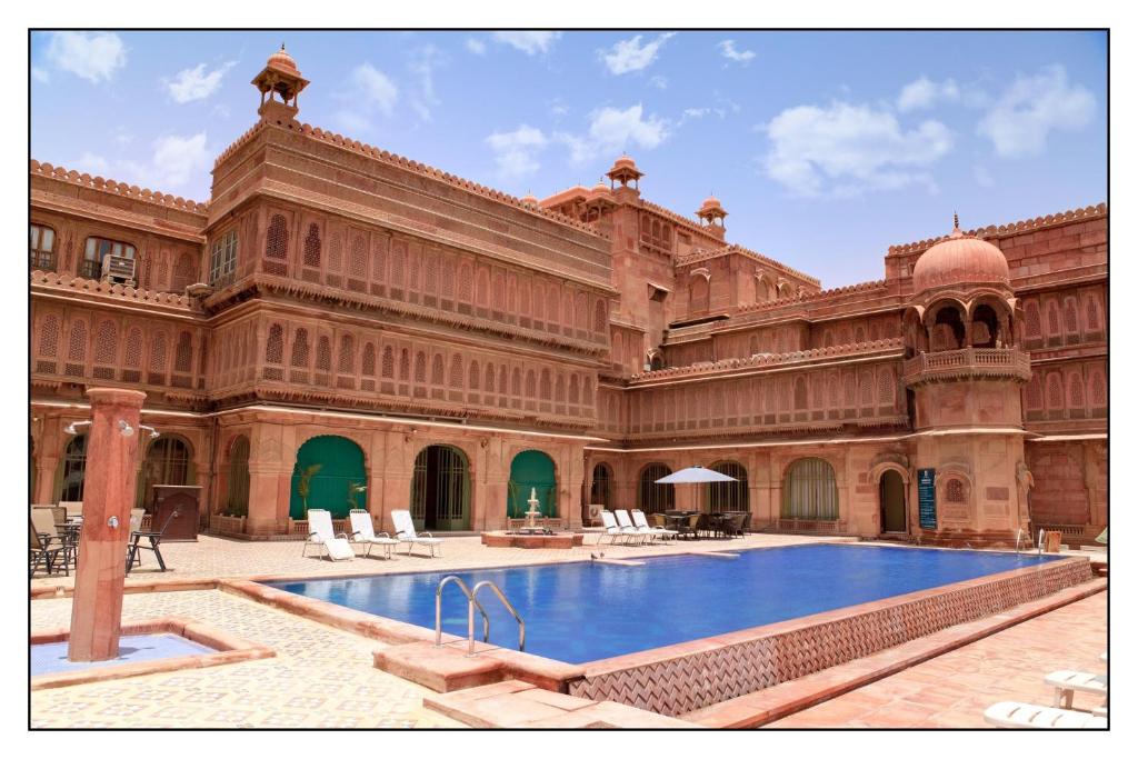 a large building with a swimming pool in a courtyard at The Laxmi Niwas Palace in Bikaner