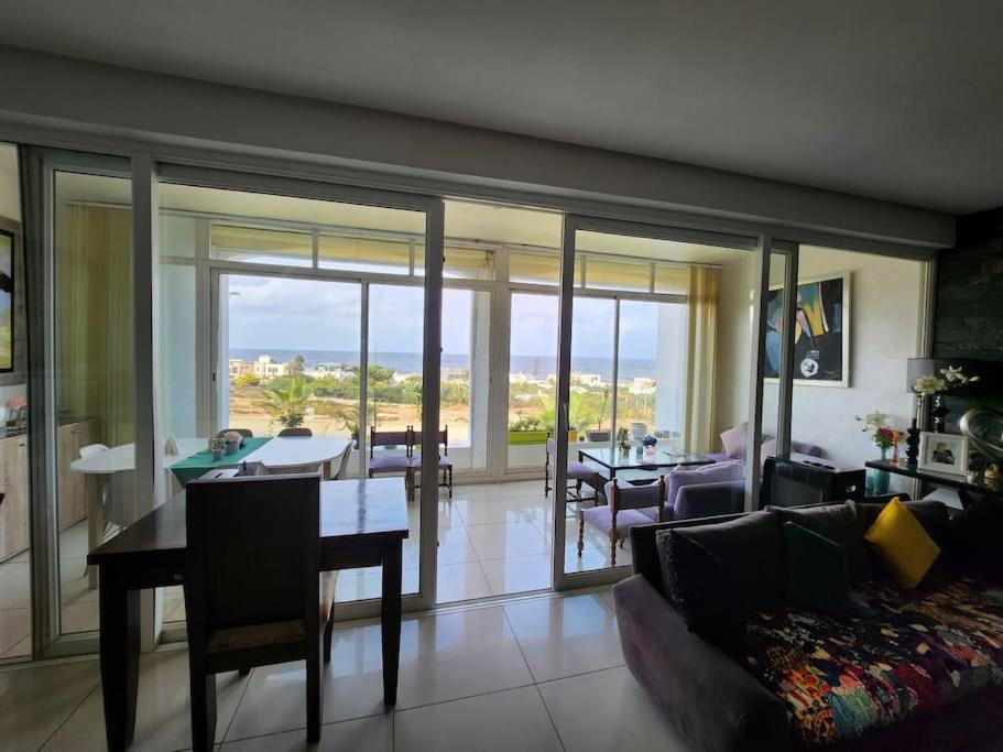 un salon avec un canapé et une table avec vue dans l'établissement Melrose Beach - Apartment with a beach view, à Dar Bouazza