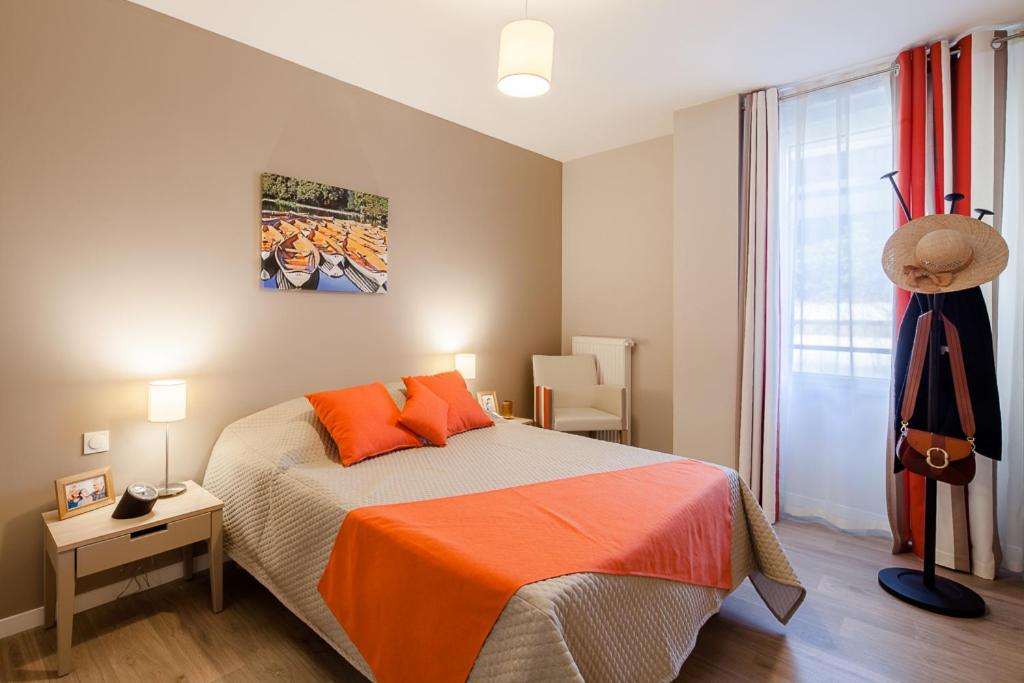 ein Schlafzimmer mit einem Bett mit orangefarbener Bettwäsche und einem Fenster in der Unterkunft Zenao Appart'hôtels Suresnes in Suresnes