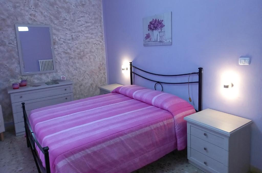 a bedroom with a pink bed and two night stands at nAnA' in Orsogna