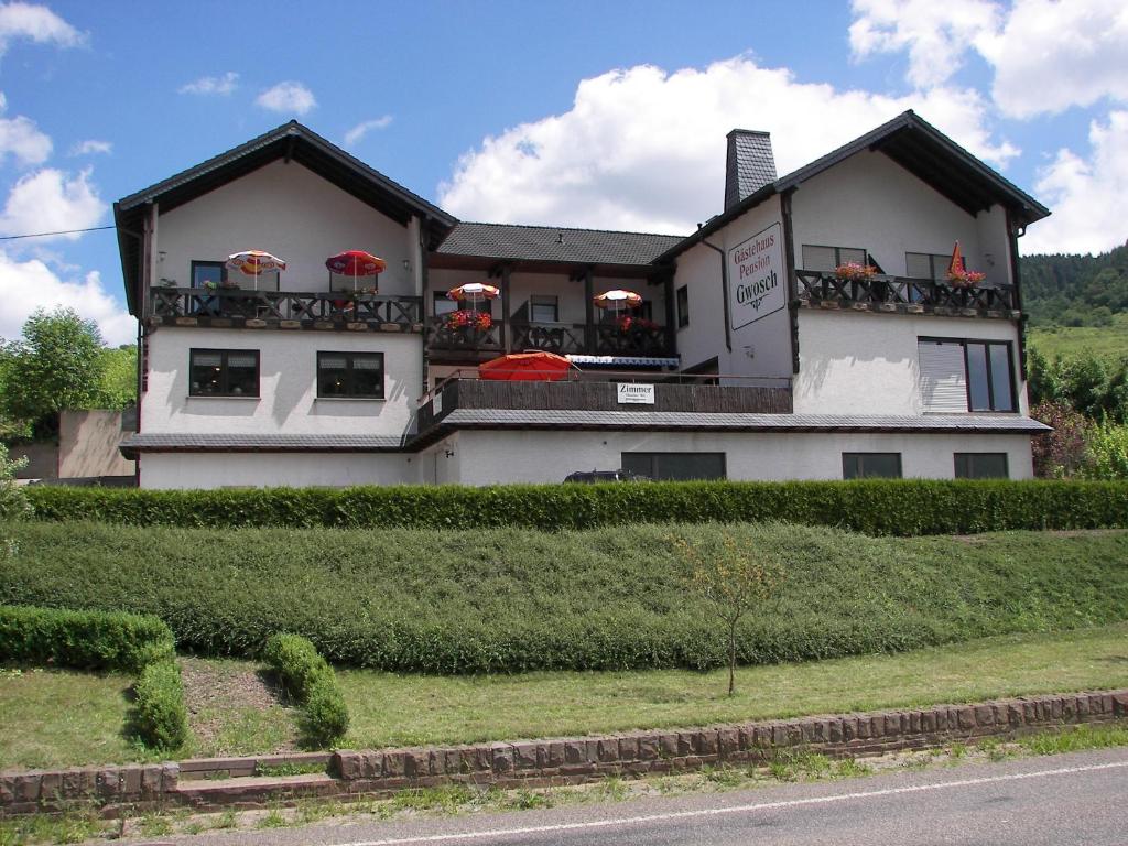 un edificio con sombrillas rojas encima en Moselpension Gwosch, en Bruttig-Fankel