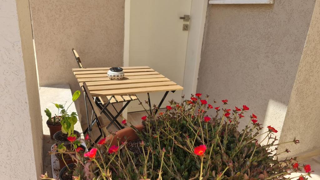 a small table with a bunch of red flowers at Alex's Desert Place in Beʼer Ora