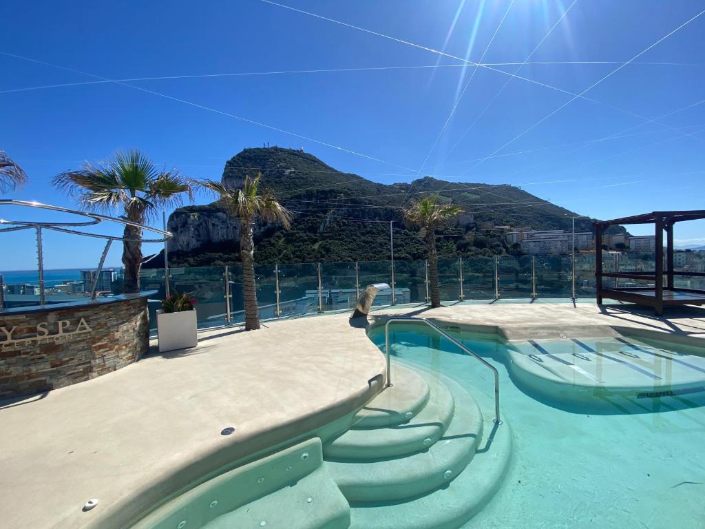una piscina con scale, palme e l'oceano di Apt with pools, spa, views and central location a Gibilterra