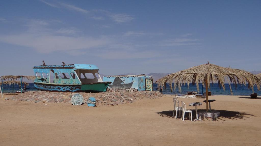 a table and chairs on a beach with a boat at OASIS Resort in Nuweiba‘ el Muzeinah
