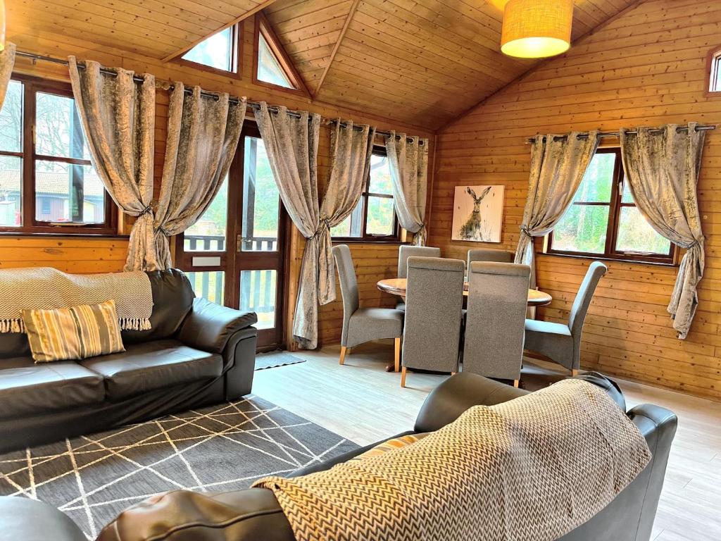 ein Wohnzimmer mit Sofas, einem Tisch und Fenstern in der Unterkunft Goldcrest 1-Hot Tub-Woodland Lodges-Carmarthenshire-Tenby in Carmarthen