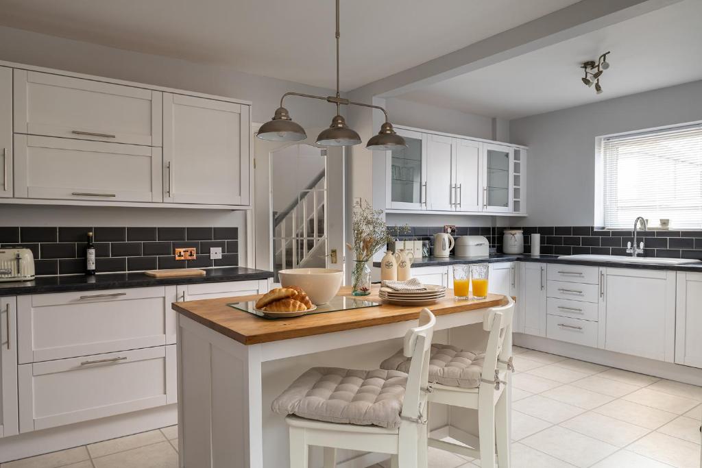 a kitchen with white cabinets and a island with a table at Lovely 3 bedroom home in Rhos on Sea in Llandrillo-yn-Rhôs