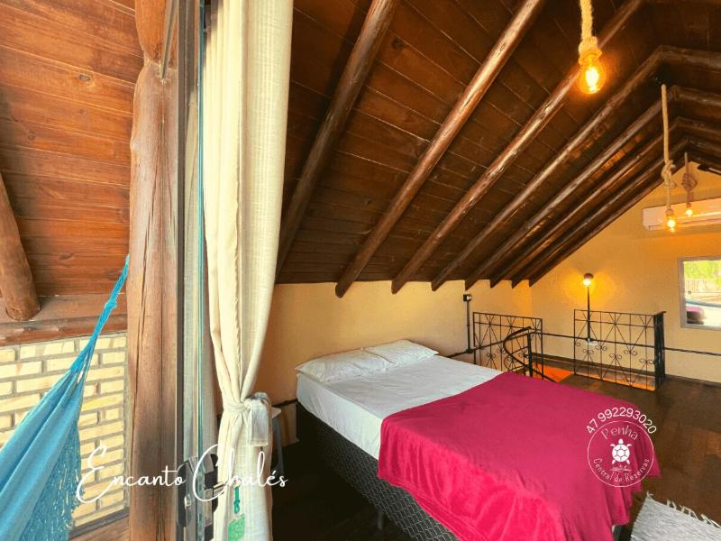 um quarto com uma cama com um cobertor vermelho em Encanto Chalés, 150 mt da Praia Grande, Penha Santa Catarina em Penha