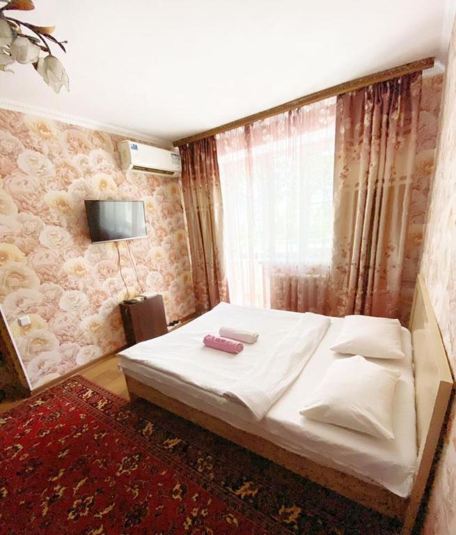a bedroom with a white bed and a tv on the wall at Квартира напротив Аэропорта in (( Turksib ))